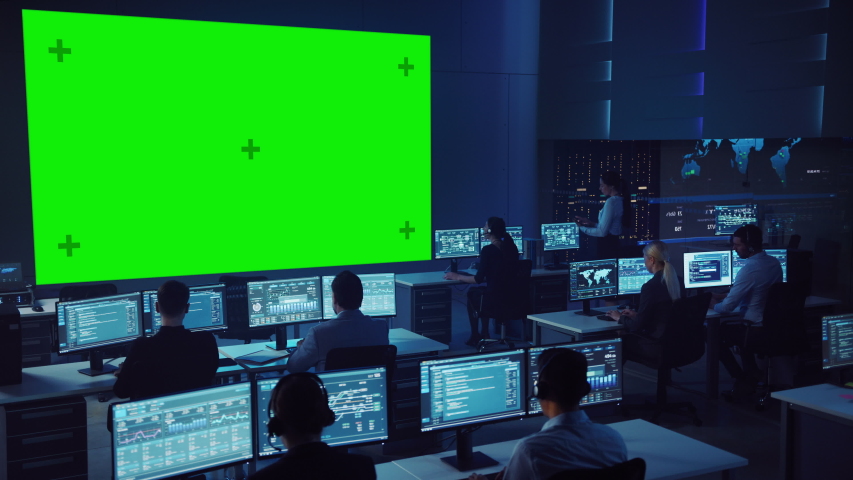 Team of Professional Computer Data Science Engineers Work on Desktops in Control and Monitoring Room. Big Display has a Green Screen Mock Up, Others Showing Charts, Graphs and Technical Statistics. | Shutterstock HD Video #1055506814