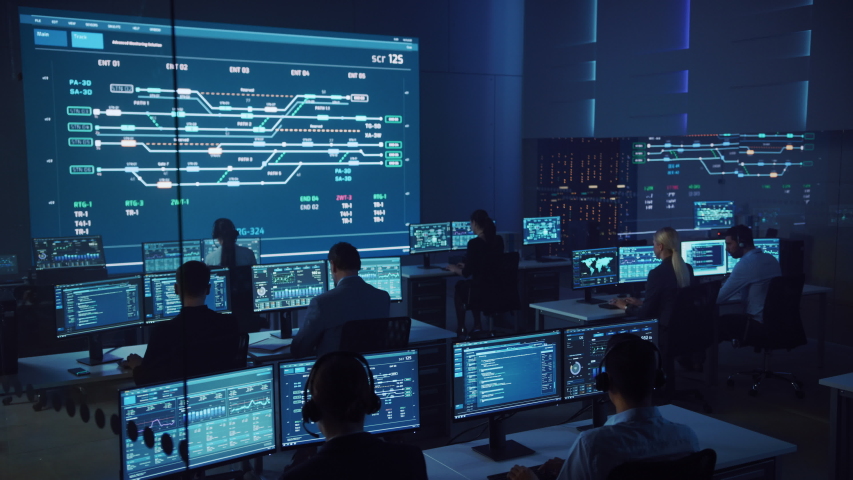 Team of Professional Computer Data Science Engineers Work on Desktops with Screens Showing Charts, Graphs, Infographics, Technical Neural Data and Statistics. Low Key Control and Monitoring Room.
