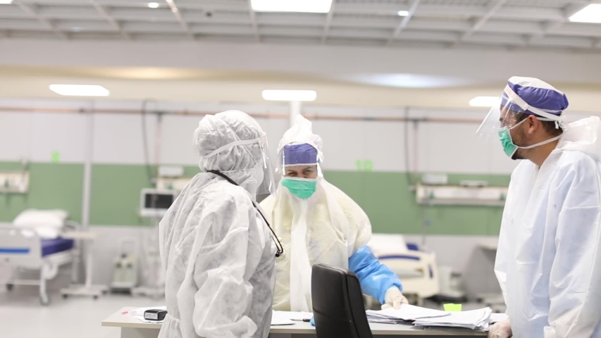 Team of nurses with face mask and protective clothing talk and smile. Group of male and female nurses in the hospital. Novel Coronavirus (COVID-19) hospitalization. Medical staff  healthcare  system.  | Shutterstock HD Video #1055509181