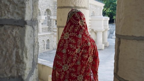 Indian Saree. View from the back of woman in red, colorful, sensual, wedding and very feminine outfit - Indian sari walks along old streets in India. Traditional national clothing of Indian women.