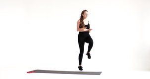 Sporty woman running on white background. Video of attractive woman in fashionable black sportswear. Dynamic movement. Side view. Sport and healthy lifestyle. material for sport classes