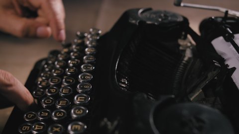 Close up shot of man typing on old vintage retro typewriter; backlit; news, media or communication concept