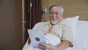 Concept tele health. Elderly Asian man using tablet and talk to family In the hospital. Patient in video conferencing with general practitioner on digital tablet. Sick man in online consultation.