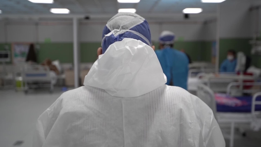 A male nurse with protective clothing, mask, and surgical cap carrying a patient bed. man doctor move a corona virus infected patient empty bed in a hospital clinic.  Be H3althy Royalty-Free Stock Footage #1055515364