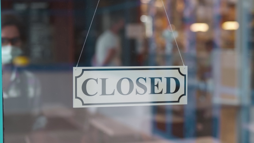 Through glass view of female business owner in safety mask hanging up sign with inscription closed on cafe door. Waitress in protective mask closing restaurant because of pandemic Royalty-Free Stock Footage #1055518799