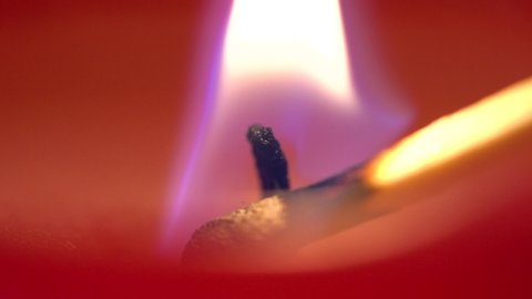 A candle is lit up by a match - macro detail