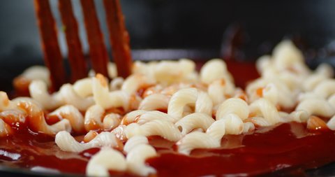 Boiled pasta cavatappi stirred with spatula with tomato sauce. Macro background.