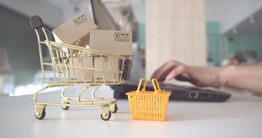 Online shopping / ecommerce and delivery service concept : Box or cartons in a shopping cart or trolley, buyer or customer uses a laptop to order things from retailer sites and pay by online payment | Shutterstock HD Video #1055531417