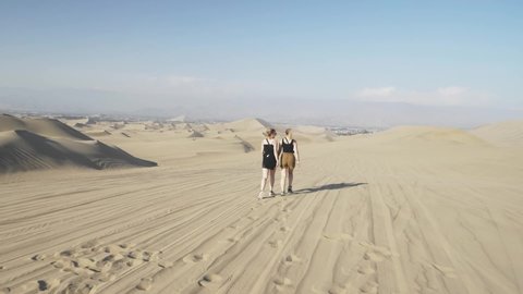 Girls Walking On Sand At Huacachina is a desert oasis.