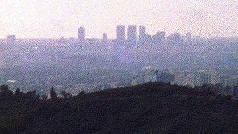 2019: Retro looking footage filmed on Super 8 shaky old looking footage of Los Angeles skyline and hills in the distance