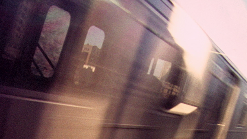 2019: Retro looking footage filmed on Super 8 on the New York City subway looking out through subway window at tracks and passing train with apartments and graffiti in the distance Royalty-Free Stock Footage #1055545358