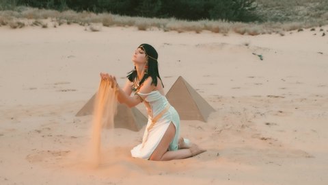 woman Queen Nefertiti. scenery Egyptian pyramids, green oasis desert. White sexy vintage dress. Gold bracelets belt traditional jewelry. goddess Cleopatra dances, plays strew yellow sand touches hands