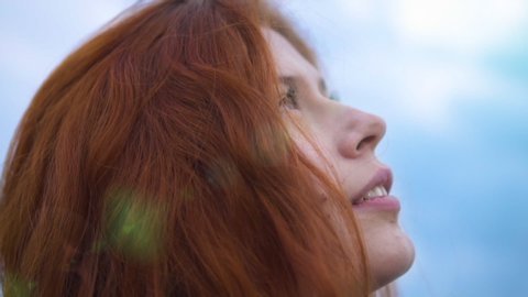 Сlose up Portrait of Beautiful Redhead Woman Exploring Spirituality Looking up Praying with Wind Blowing Hair Lens Flare Pray Prayer Sun Flare