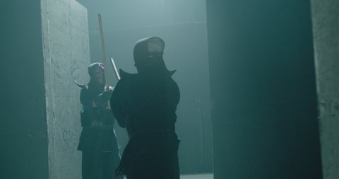 Japanese kendo fighters with bamboo swords competing  in the fog in dark mystic industrial building . Epic battle video with two kendo fighter . Shot on ARRI Alexa Cinema Camera in slow motion .