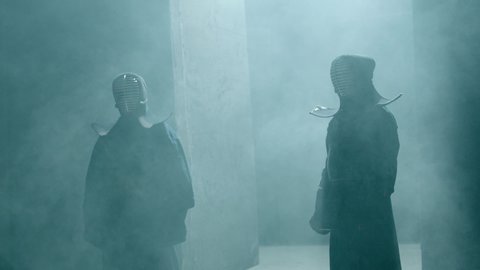 Portrait Of two Japanese Kendo Fighter stay inside dark place before battle . Epic Kendo warrior stands in armor in the fog and looking at the camera with his fire shinai . Dolly Gimbal Shot on Arri A