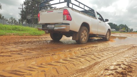 Brits / South Africa - 02 10 2020: A farmer's pickup truck driving through a puddle of water on a muddy farm dirt road during rainy season