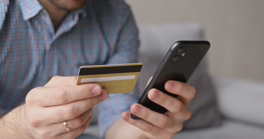 Close up view male hands holding credit card and smart phone makes purchase enjoy on-line shopping. Modern tech, e-bank application, safe payment, buying distantly easy and comfortable usage concept Royalty-Free Stock Footage #1055572043