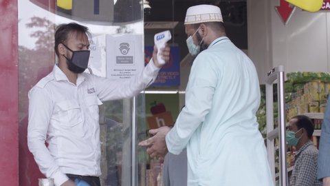 Muslim customers walk in the super store and get their temperature checked by laser thermometer as a safety measure during Covid-19 Lockdown. Karachi, Pakistan. 25th June 2020