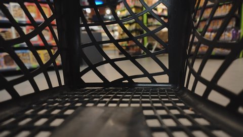 Timelapse. View from inside empty handheld shopping cart basket crate in mall center. Commerce, sales. Man walks through store's area. Customers go in search of goods. Buyers walk around the territory