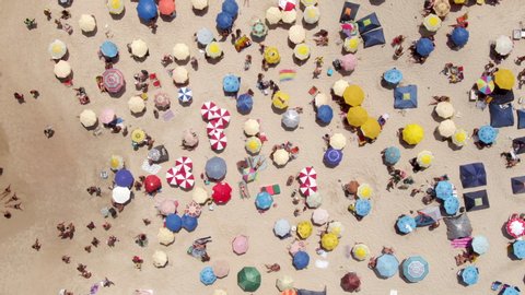 Top down aerial view of colourful sun umbrellas and people relaxing at the beach in Rio de Janeiro, Brazil, fun tropical vacation and summer background. 