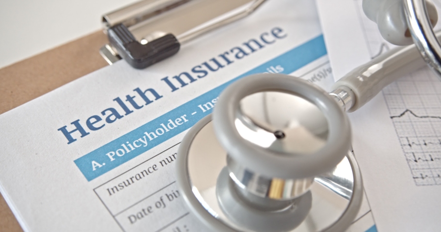 Health insurance form on a table in a doctor or physician office. Stethoscope on an insurance agreement, paper that has a plan or policy covers or insure the risk of a person incurring medical expense | Shutterstock HD Video #1055582630