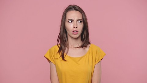 Smiling cute charming young woman girl 20s years old in yellow t-shirt look aside around one guy nice other disapprovingly different emotions like dislike isolated on pastel pink background studio 