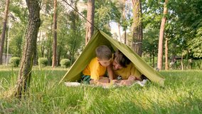 Father with son in tent on green grass discovering flora and fauna. Father with son lying in camp tent. Two travelers having fun in tent. Traveling close to home. One parent family - Powered by Shutterstock - Get 15% off with code: PIKWIZARD15