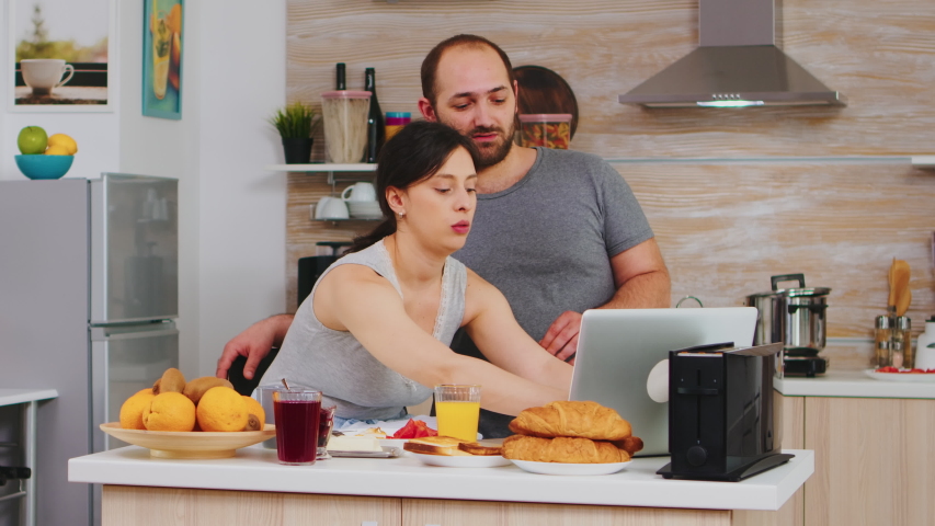 Pretty woman shopping online via interet during breakfast with husband, paying with credit card. Entering information, customer using e-commerce technology buying stuff on the web, cosumerism banking