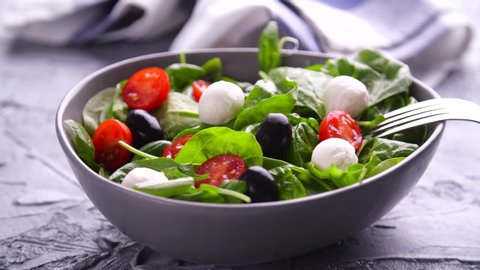 Vegetarian and, organic food concept. Caprese Italian or Mediterranean salad. Tomato mozzarella basil leaves black olives and olive oil rotate