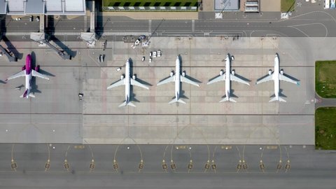 Wroclaw, Poland - June 17, 2020: Aerial flat lay, top down view of airplanes parked on airport apron in front of modern airport in Wroclaw. Slide from left to right camera shot from the drone