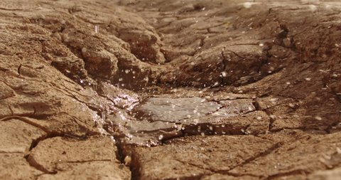 Water drops falling on cracked ground of dried lake. Close up shot of dried mud after erosion and desertification - ecology, save our planet concept 4k footage
