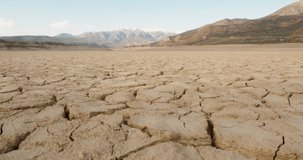 Dynamic shot of cracked soil ground of dried lake or river in mountains. Land destroyed by erosion and global warming - ecological issues concept 4k footage