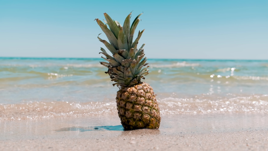 Pineapple on the beach. Pineapple fruit in the sea waves. Leisure in summer and Summer vacation concept. 