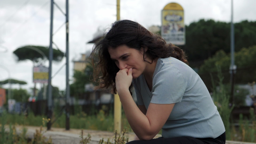 sad desperate young woman crying sitting by the roadside - slow motion