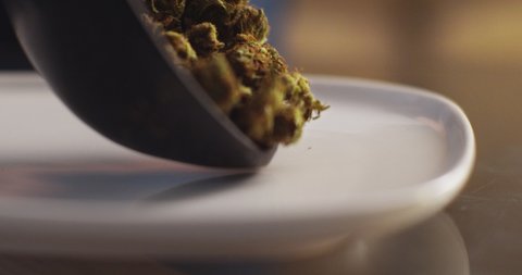 Close up of cannabis buds being spread on a white plate, shallow depth of field, slow motion,  Marijuana, weed, smoking drugs concept. CBD, THC footage