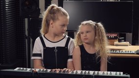 Two girls laugh and learn to play a musical instrument. Playing the synthesizer.