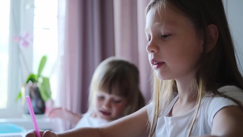 In elementary school: portrait of a cute girl writes in an exercise book, smiles.