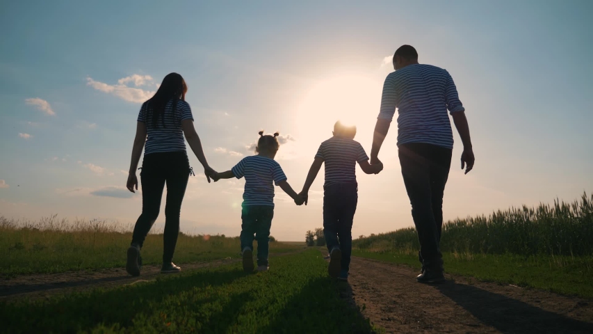 Happy family. Lovely couple with kids strolling at sunset in the evening around the field. The concept is the teamwork of hiking, active lifestyle, parenting. Royalty-Free Stock Footage #1055641196