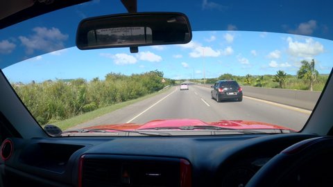BRIDGETOWN, BARBADOS, CARIBBEAN ISLANDS, DECEMBER 2019: POV: Unrecognizable tourist on fun road trip across Barbados drives down a highway running across the island. Jeep drive across tropical island
