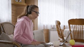 Caucasian woman in a hoodie communicates with colleagues from home using a laptop during a coronavirus pandemic. Remote work from home on the couch or freelance. Self-isolation during pandemic concept