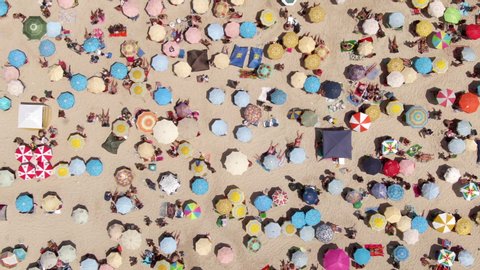 Top down aerial view of colourful sun umbrellas and people relaxing at the beach in Rio de Janeiro, Brazil, fun tropical vacation and summer background. 