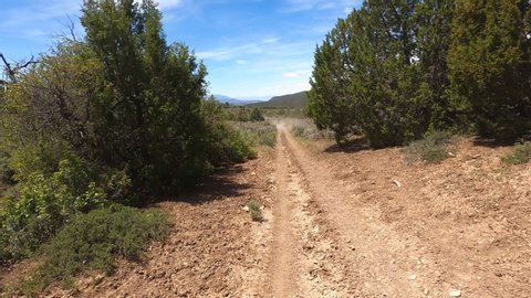 Outdoor off road recreation dusty mountain trail OHV 4K POV. Off road trail riding in 4x4 all terrain vehicle for sport and recreation. Dry arid landscape. Grass lands, rocky terrain and sand dunes.