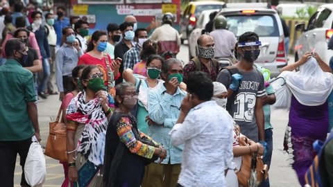 MUMBAI/INDIA- JUNE 10, 2020: Commuters wearing a facemask wait to board a public transport bus in Mumbai. India has begun gradually lifting its restrictions imposed by the government.
