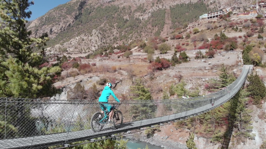 Mountain bikers crossing a swinging bridge in Nepal.