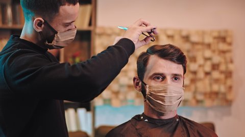 Charismatic guy with protective mask and barber man with protective mask doing a hair cut in the quarantine at home Covid-19. 4k 库存视频