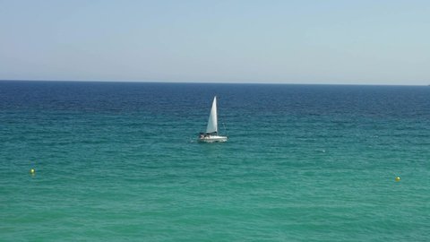 Sailboat sailing on crystal clear water of the Mediterranean sea, on summertime at Barcelona Spain