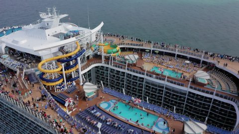 Royal Caribbean Cruise liner, Miami, USA, May 2019. 4K aerial of upper deck of luxury cruise ship with crowd of tourists having fun at water park and playgrounds during their vacation. Voyage holidays