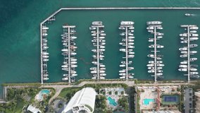 Water sport and transportation concept. Overhead view on white luxury yachts in marina. 4K aerial beautiful green water in the bay. Beautiful slow motion drone video for sailing business. Miami, USA
