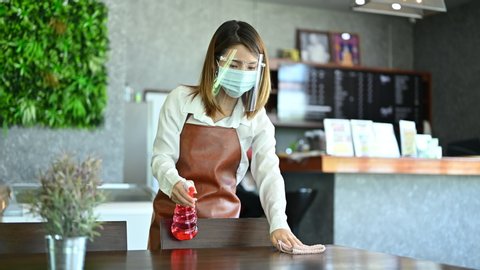 New normal startup small business Portrait of Asian woman barista wearing protection mask and face shield cleaning table in coffee shop while opening in social distancing Stock Video