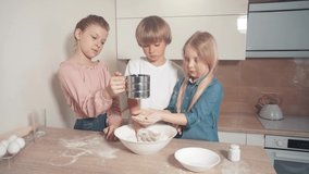 Cute three children learning to cook dough. Adding flour to the dough.